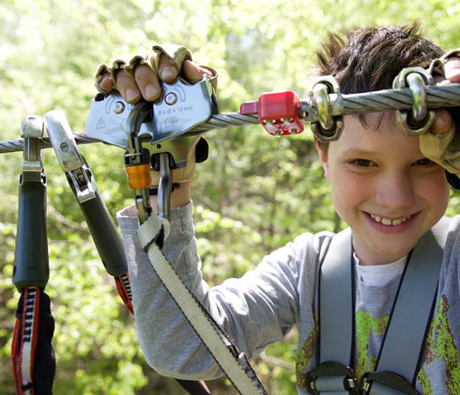 Lachender Junge mit Ausrüstung am Zipline-Seil